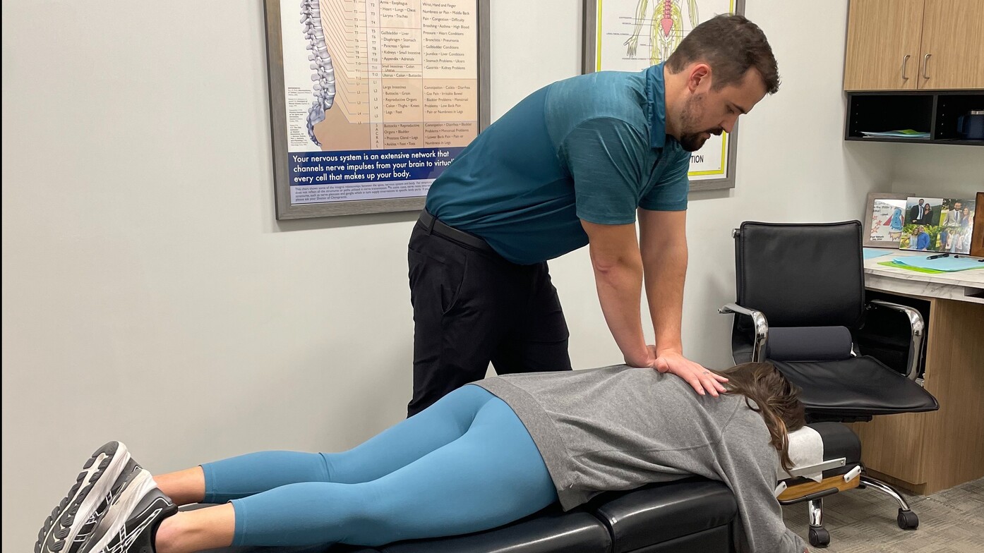 A chiropractor performs a spinal adjustment on a patient lying on a treatment table, promoting natural back pain relief for Waukee residents.