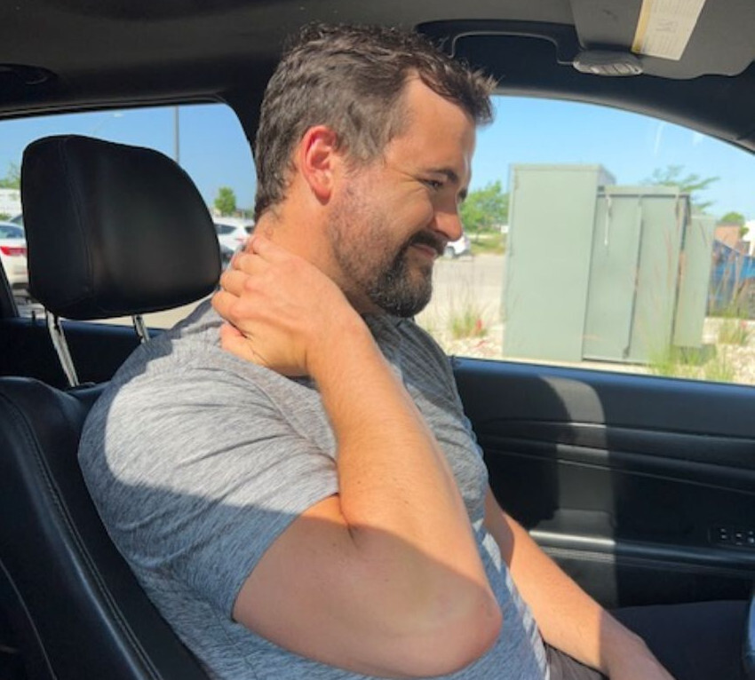 A man in a car rubs his neck in discomfort after a car accident in Waukee, Iowa, highlighting the need for chiropractic care.